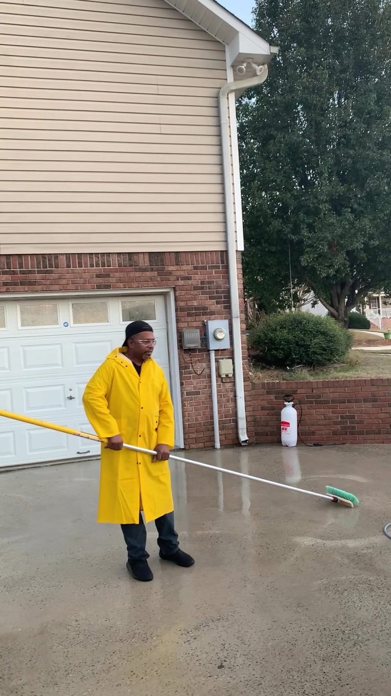 Crew member in a yellow raincoat brushing a freshly cleaned porch